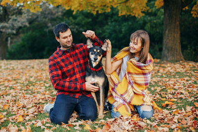Young man with dog standing in park during autumn