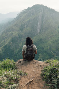 Rear view of man sitting on mountain