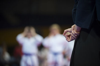 Midsection of person with hands behind back standing in stadium