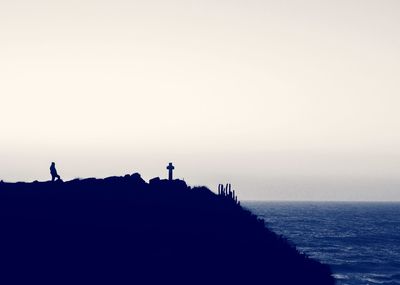 Silhouette people on sea against clear sky at sunset