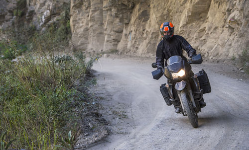 Man driving touring motorbike on dirt road, santa teresa, piura, peru