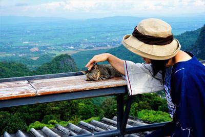 Woman touching domestic cat while standing against railing