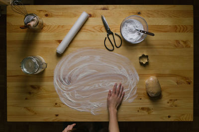 Top view of a young woman making christmas cookies on a wooden table