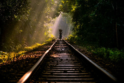 Rear view of woman walking on railroad tracks