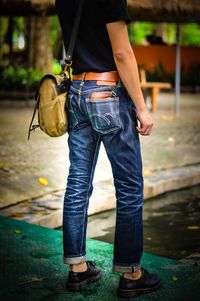 Low section of man holding umbrella standing in city