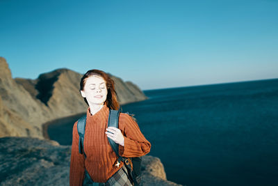 Woman standing by sea against clear sky