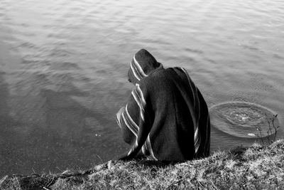 Rear view of man covered in scarf at riverbank