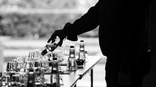 Midsection of silhouette man pouring drink in wineglass on table