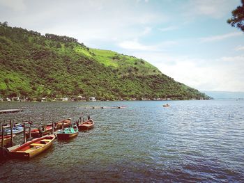 Boats moored at sea shore against sky