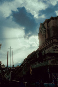 Low angle view of cross amidst buildings against sky