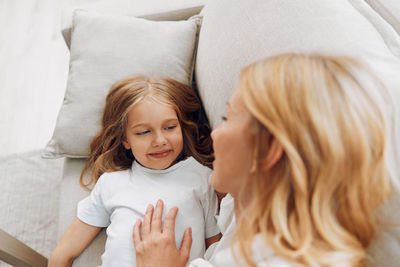 Side view of young woman sitting on bed at home