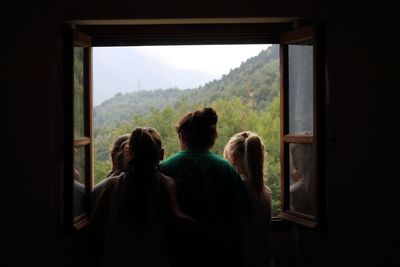 Rear view of people looking through window