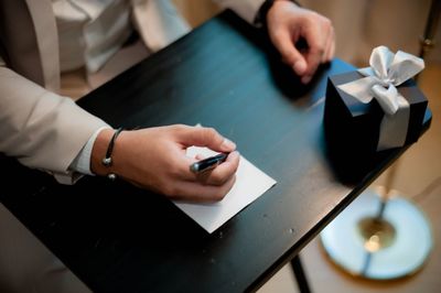 Midsection of man with pen and paper by gift on table