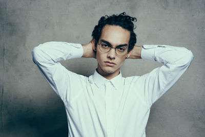 Portrait of young man standing against wall