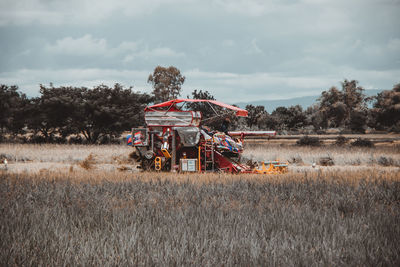 Combine harvester at farm against sky