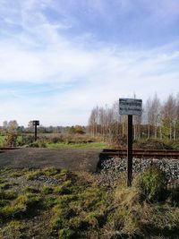 Information sign on field against sky