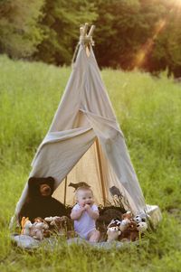 Full length of baby boy with toys in tent on grass