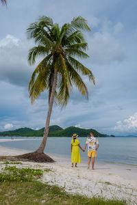 Rear view of woman standing at beach against sky