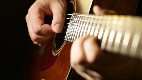 Midsection of man playing guitar