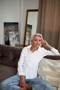 Delighted mature woman in stylish clothes on sofa