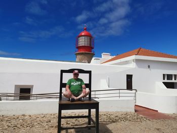 Man sitting on bench against building