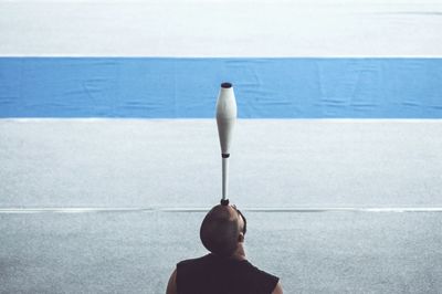 Rear view of man balancing juggling pin on head