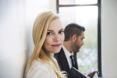 Portrait of businesswoman standing by colleague in office