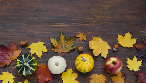 Decorative pumpkins on wooden background with bright autumn leaves  thanksgiving or halloween