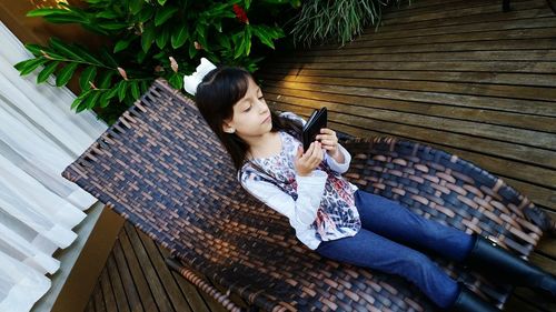 High angle view of girl using digital table while sitting on chair at home