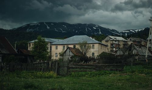 Abandoned house on field by mountains against sky