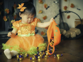 Baby girl holding jack o lantern basket with candies at home