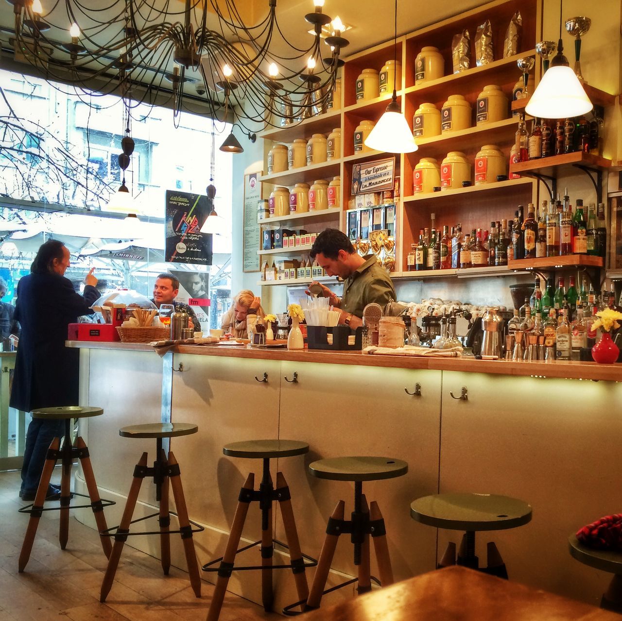 indoors, table, restaurant, chair, food and drink, sitting, illuminated, arrangement, retail, men, person, dining table, variation, glass - material, lighting equipment, sidewalk cafe, built structure, food, architecture