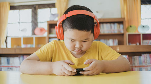 Cute boy using mobile phone at table