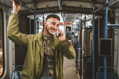 People, lifestyle, travel and public transport. attractive man talking on the phone in public bus.