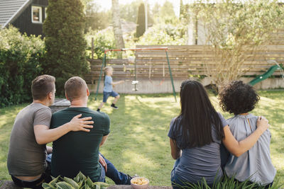 Rear view of people sitting in yard