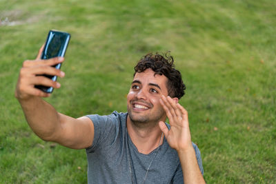 Portrait of young man using mobile phone in grass