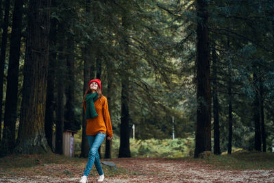 Woman standing by trees in forest