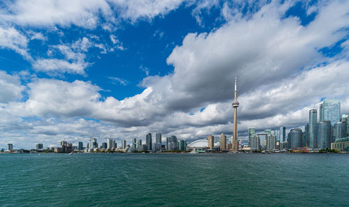 City at waterfront against cloudy sky