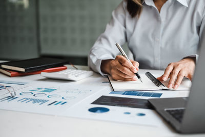 Midsection of businessman working on table