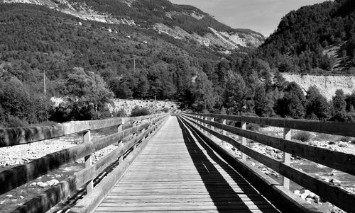 Narrow footbridge along trees on mountains