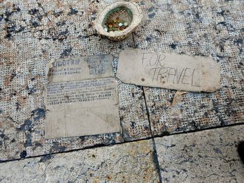 Close-up of cardboard paper and coins collected in hat on floor