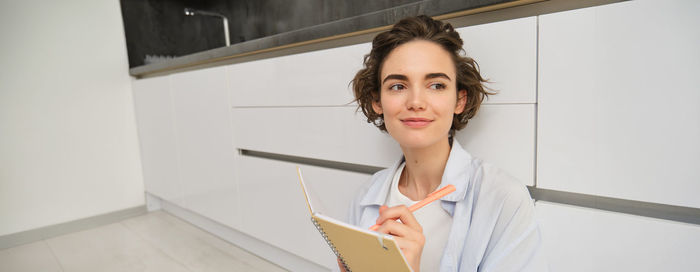 Portrait of young woman standing against wall