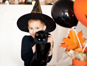 Portrait of boy holding cat at home