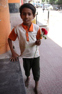 Full length portrait of boy holding roses on walkway