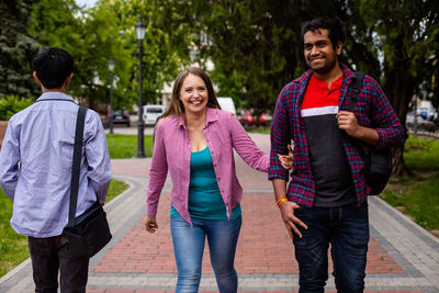 Full length of a smiling young couple walking on footpath