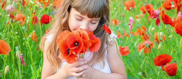 Close-up of young woman blowing flowers