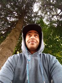 Portrait of smiling young man standing against trees