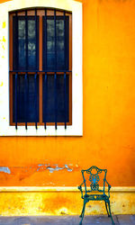 Empty chairs and table against window of building