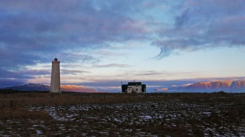 Buildings on field against sky during sunset