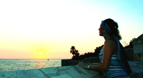 Side view of young woman looking at sea against sky